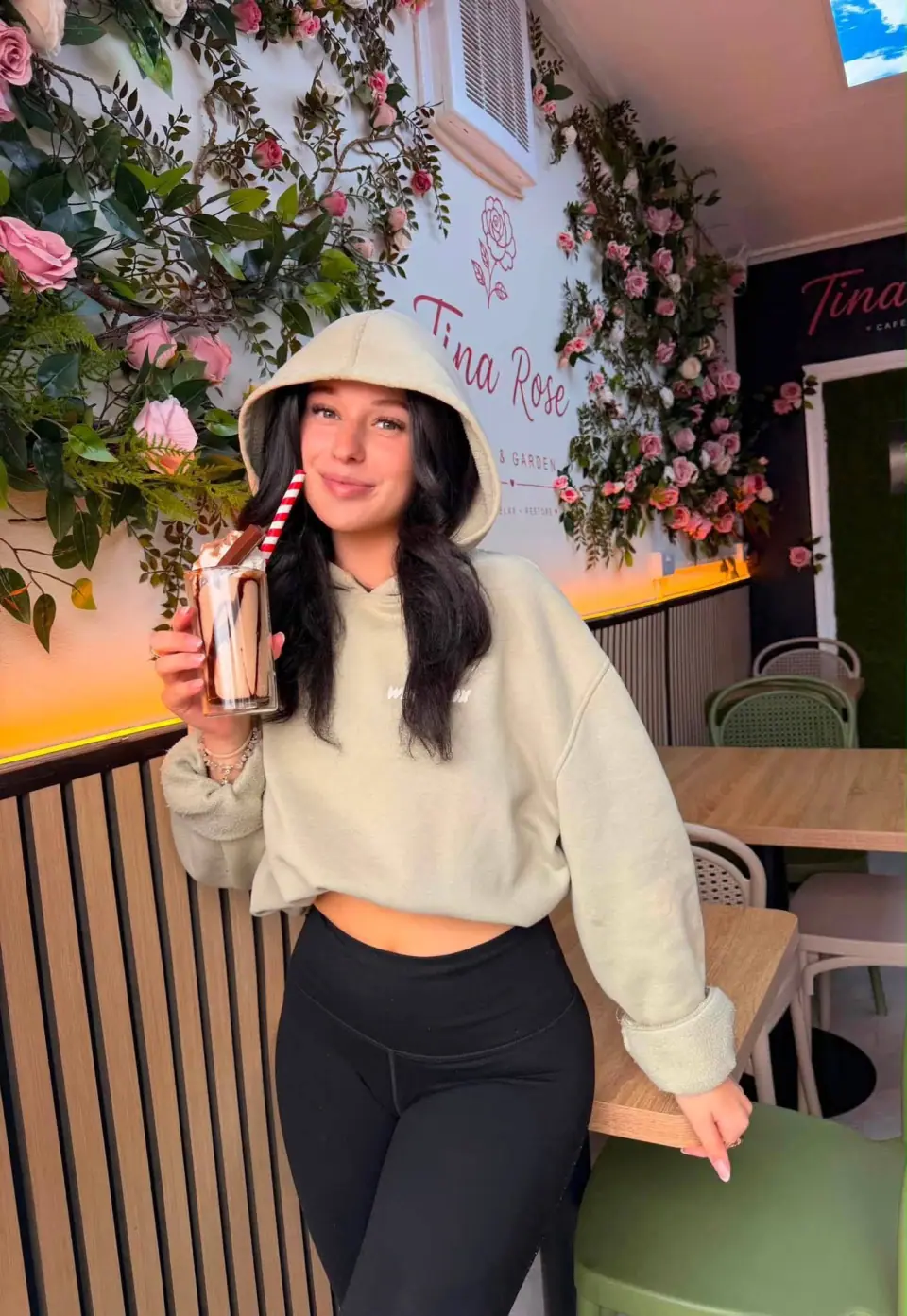 A guest enjoying a chocolate milkshake beside Tina Rose's floral wall