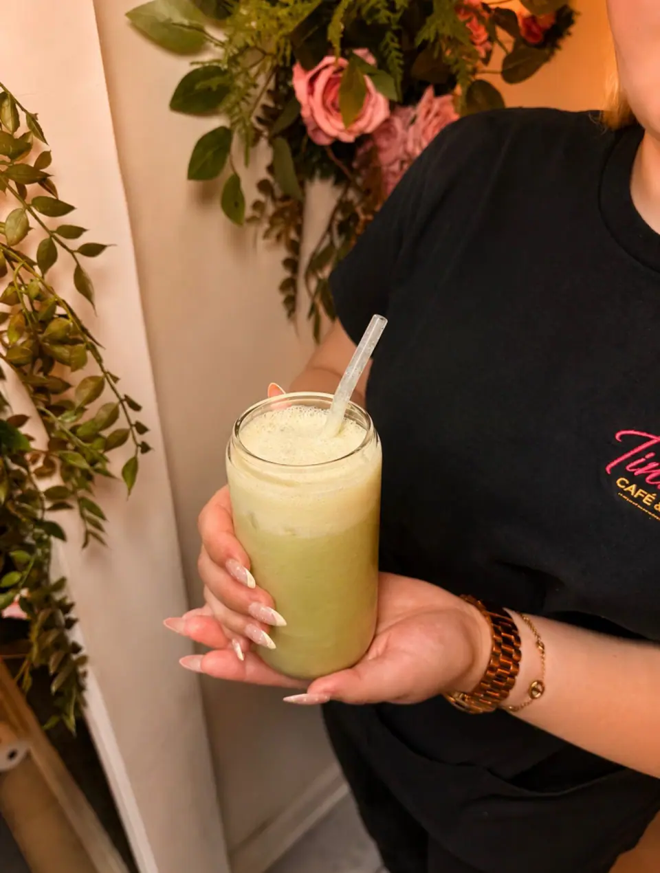 A Tina Rose team member serving a frothy green matcha drink