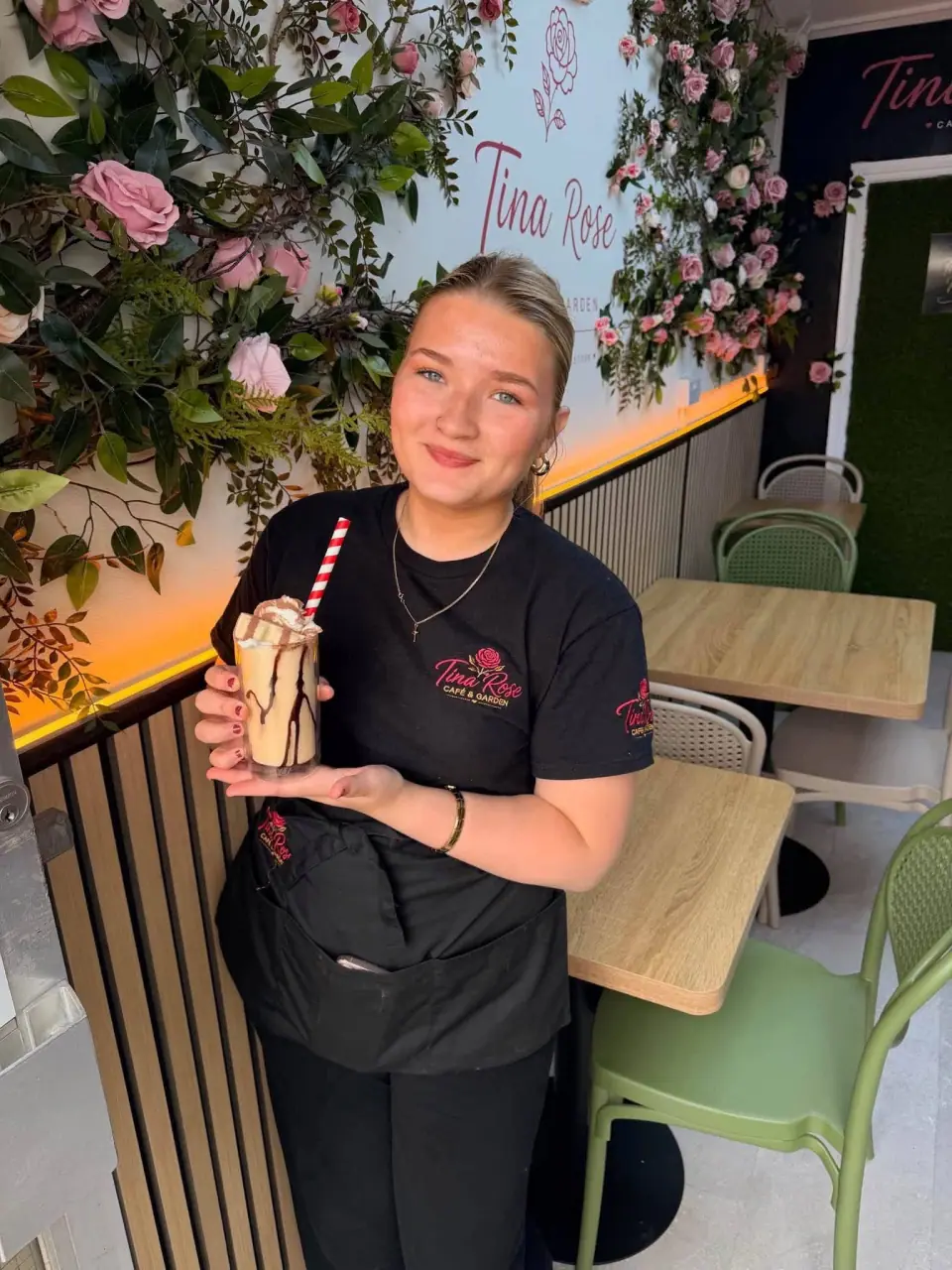 A smiling Tina Rose team member holding a chocolate milkshake